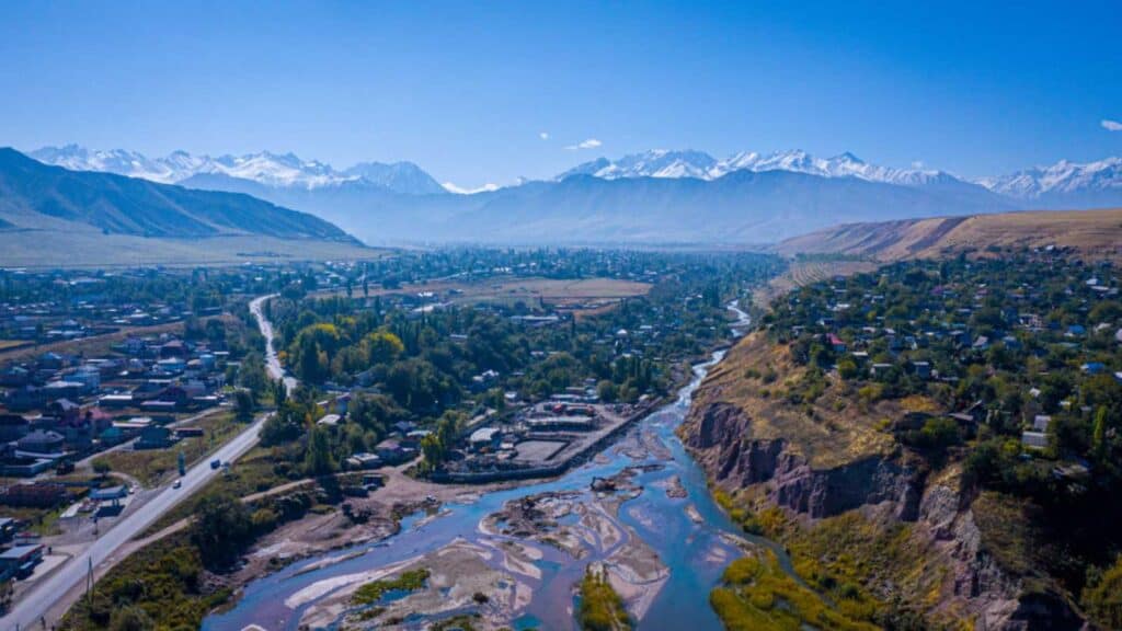 Kyrgyzstan. Bishkek. The river flows into the gorge. Around you can see the picturesque houses of local residents. On the horizon mountains with snow. The atmosphere is relaxing. The sky without cloud