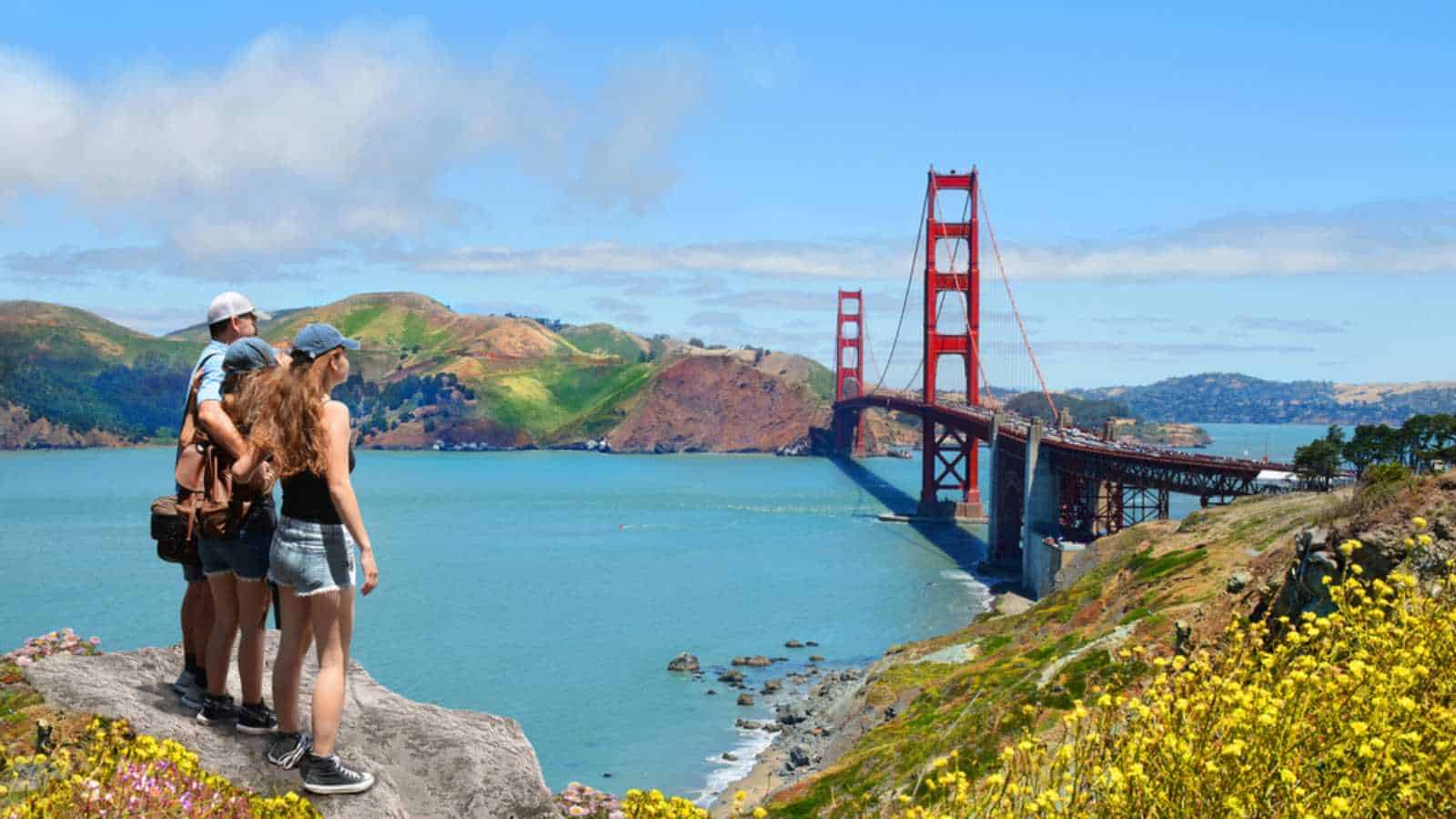 Father with arms around his family looking at beautiful summer mountains landscape, on hiking trip .Golden Gate Bridge, over Pacific Ocean, San Francisco, California, USA