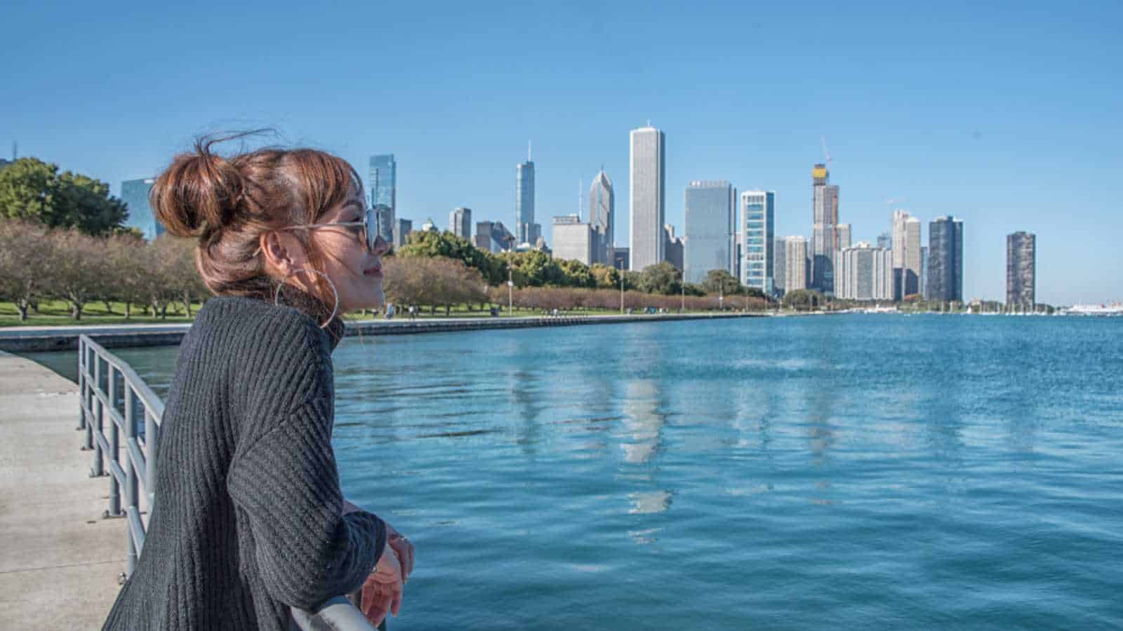 Tourist woman visit architecture of Chicago she walking Lincoln Park near lake. Chicago, Illinois, USA.