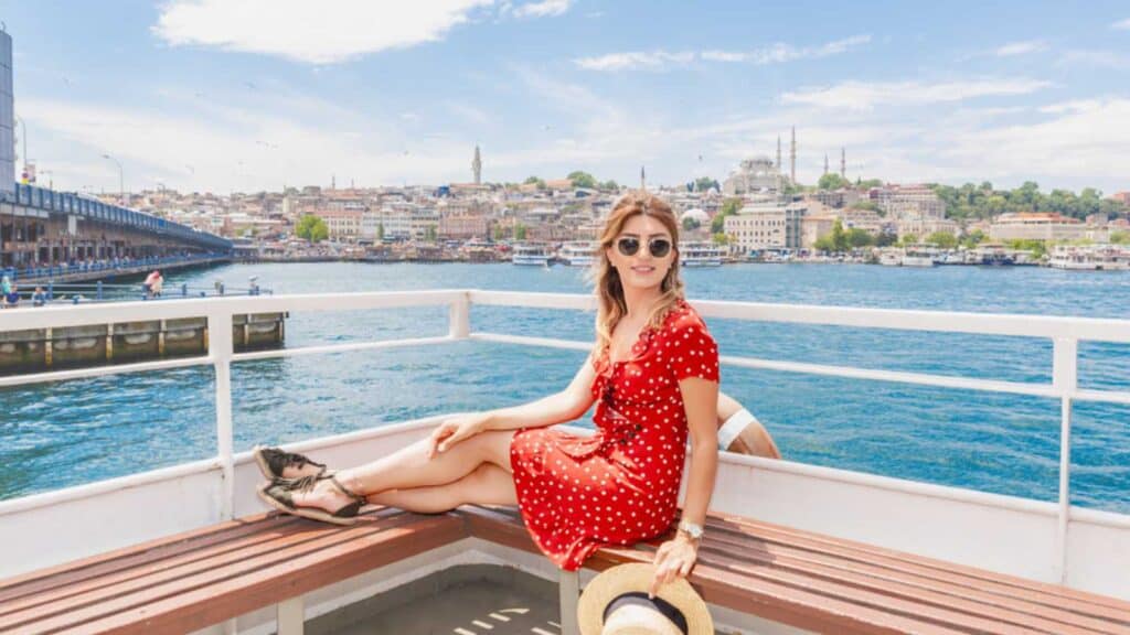 Beautiful woman cruises in ferry with view Galata bridge,Suleymaniye Mosque and Eminonu Town in Istanbul,Turkey