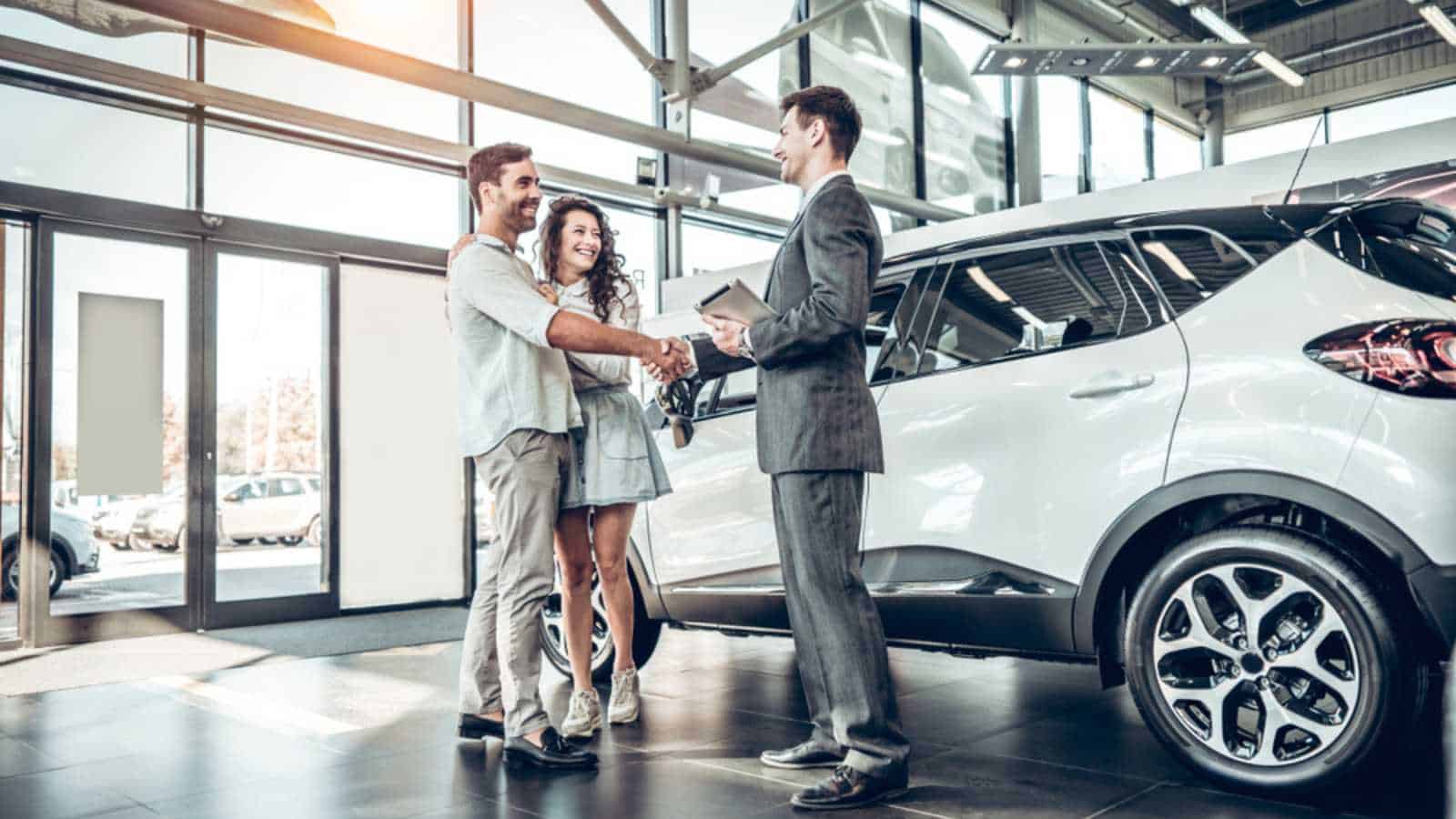 Salesman showing car to couples