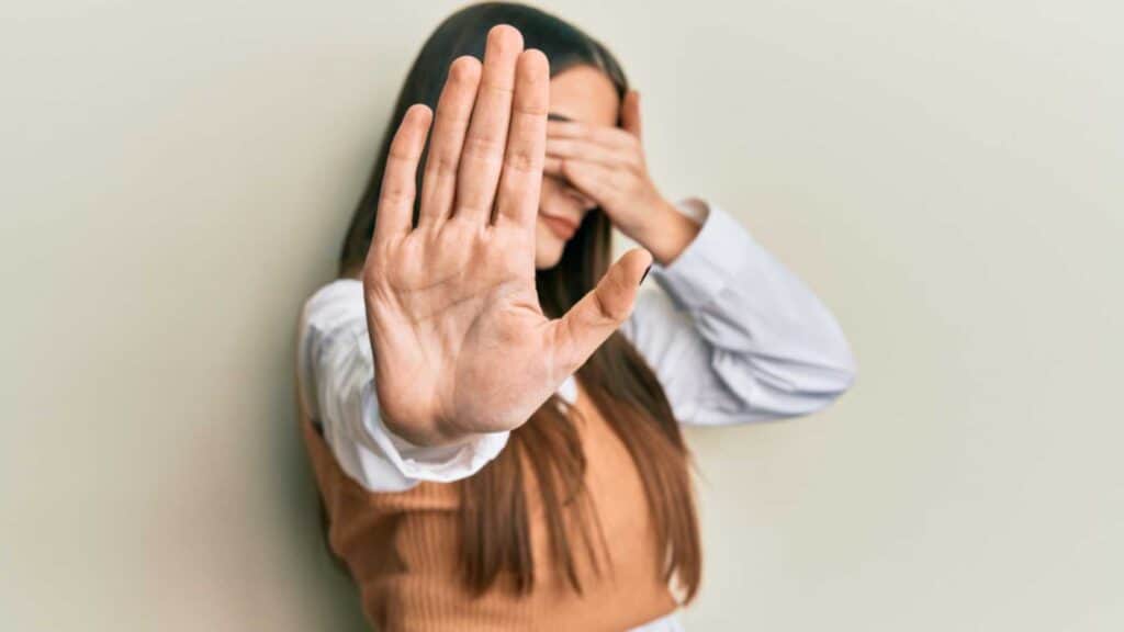 Woman covering eyes with hands and doing stop gesture