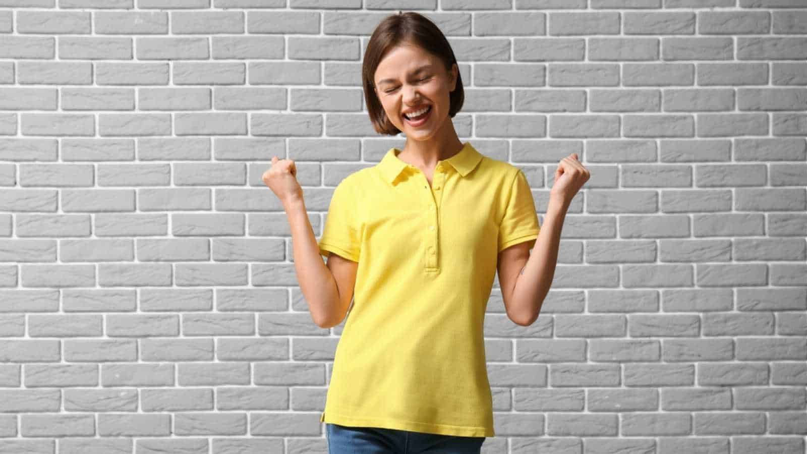 Happy young woman in stylish polo shirt on brick background