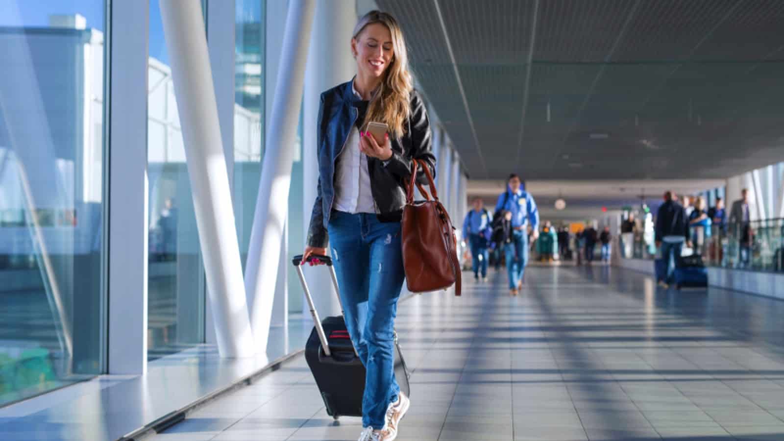Woman holding suitcase and walking in airport