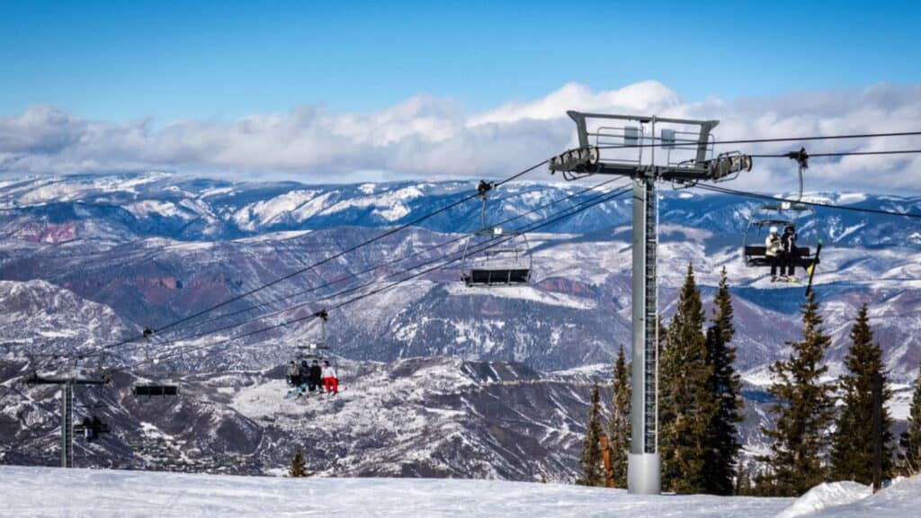 Snowmass Village, Colorado - January 6, 2020: Skiers and snowboarders ascend the Elk Camp chairlift at the Aspen Snowmass ski resort, in the Rocky Mountains of Colorado on a partly cloudy winter day.