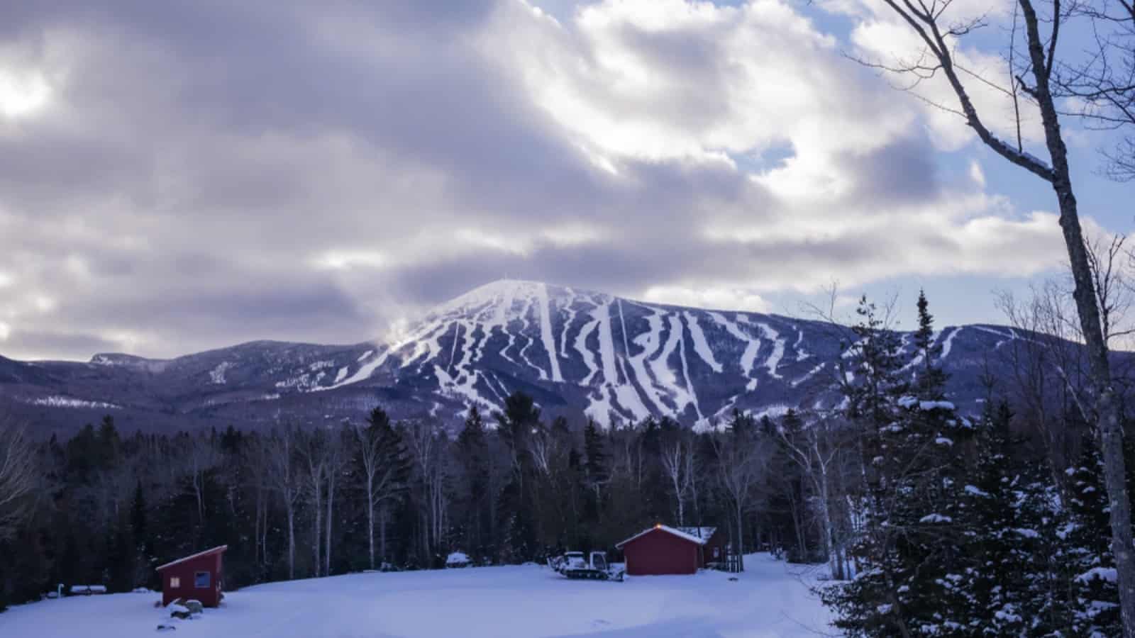 Carrabassett Valley, Maine / USA - January 7 2020: Dramatic clouds light up the slopes at Sugarloaf ski resort in western Maine. Photographed from the race trail at the Outdoor Center.