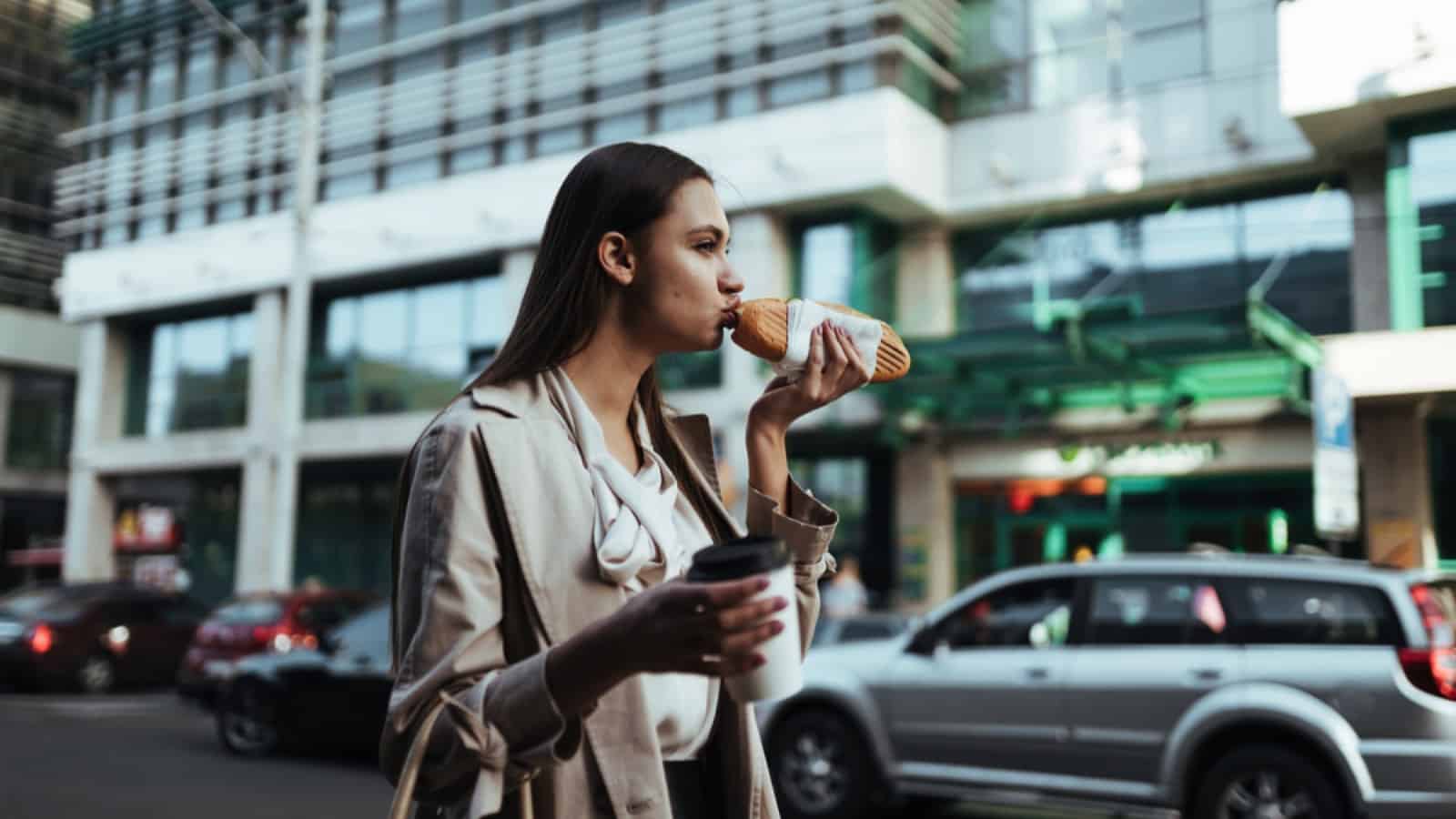 Woman eating and walking along pavement