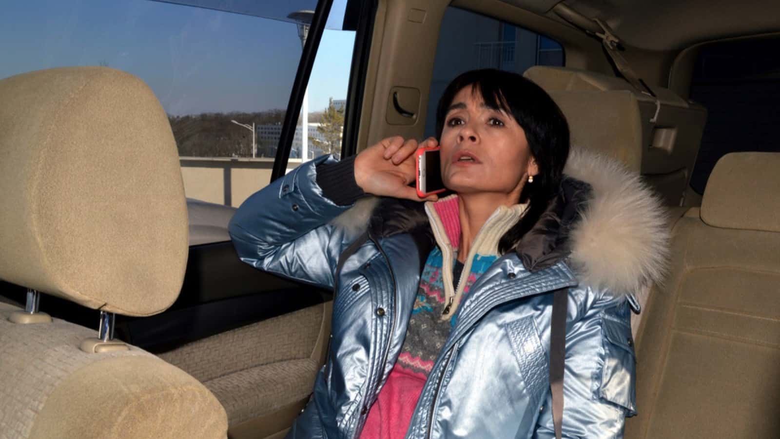 Worried scared woman passenger sitting on back seat of car
